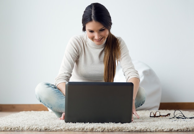 Schöne junge Frau arbeitet an ihrem Laptop zu Hause.