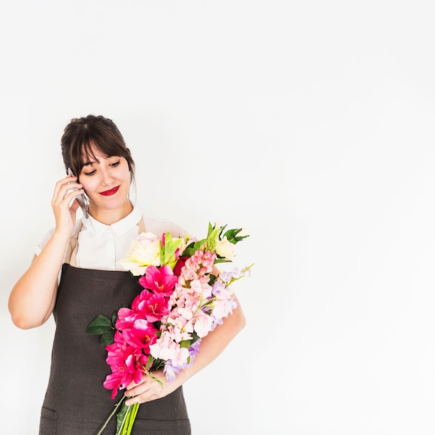 Schöne junge Frau, die am Handy hält Blumenstrauß spricht