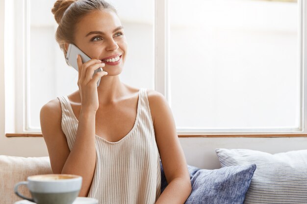 Schöne junge Frau, die am Telefon spricht