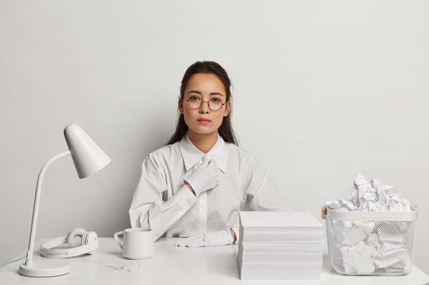 Schöne junge Frau, die an ihrem Schreibtisch studiert