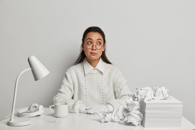 Schöne junge Frau, die an ihrem Schreibtisch studiert