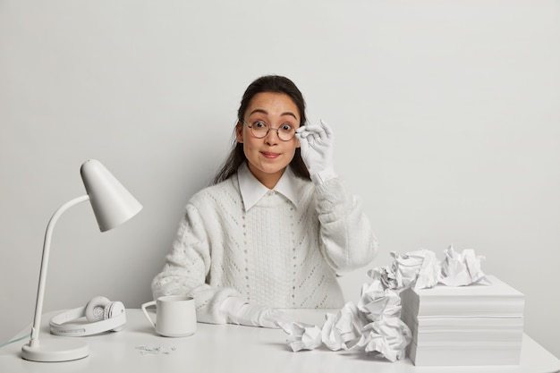 Schöne junge Frau, die an ihrem Schreibtisch studiert