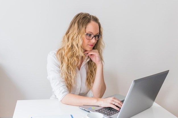 Schöne junge Frau, die auf Laptop grast