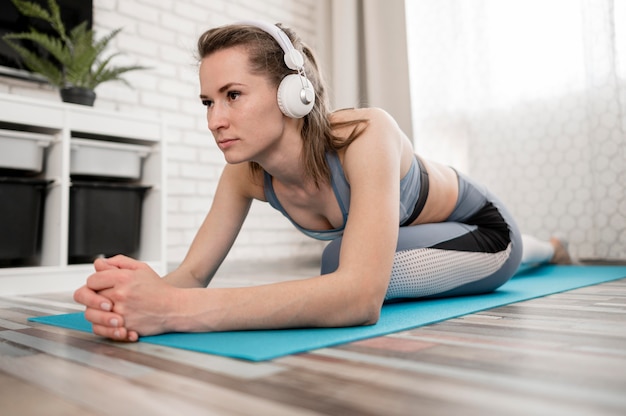 Schöne junge Frau, die auf Yogamatte trainiert