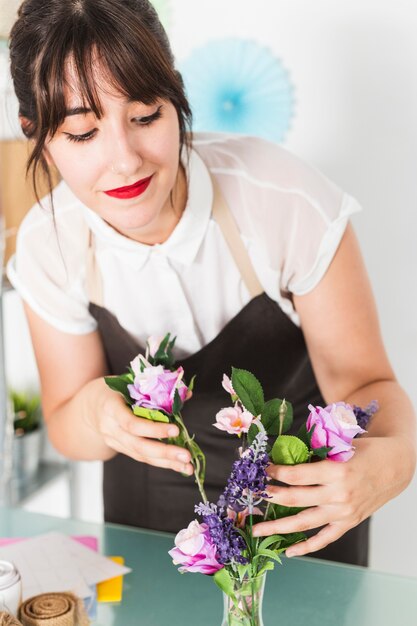 Schöne junge Frau, die Blumen in Vase einsetzt