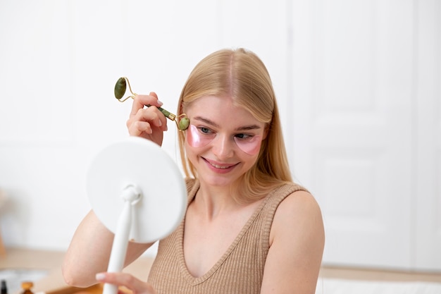 Schöne junge Frau, die ein Gesichtspflegeprodukt verwendet