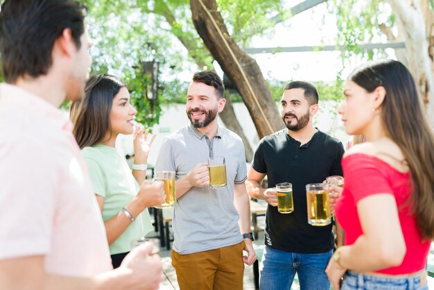 Schöne junge Frau, die ihren Freunden eine lustige Geschichte erzählt. Gruppe von Freunden, die sich während eines Wiedersehens in einer Bar unterhalten