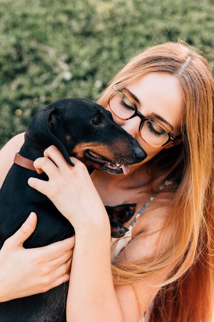 Schöne junge Frau, die ihren Hund küsst