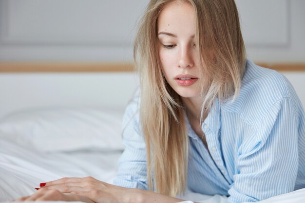 Schöne junge Frau, die im Bett entspannt