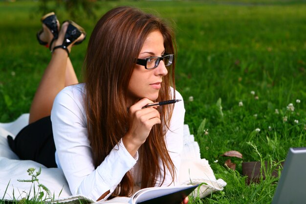 Schöne junge Frau, die im Park studing ist