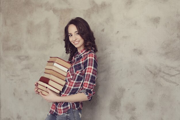 Schöne junge Frau, die mit Büchern aufwirft