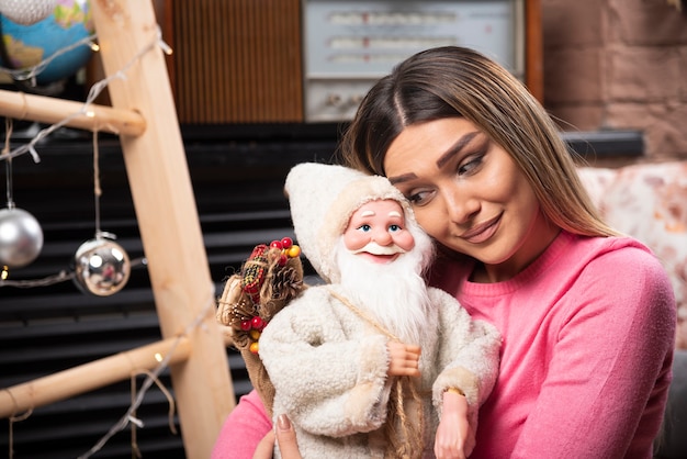 Schöne junge Frau, die Puppe zu Hause betrachtet.