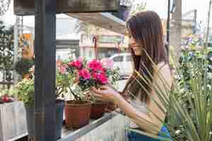 Kostenloses Foto schöne junge frau, die schöne rosa blume betrachtet