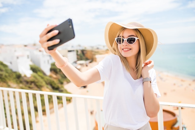 Schöne junge Frau, die selfie am Telefon am Strand tut