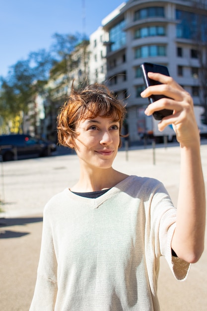 Schöne junge Frau, die selfie mit Smartphone nimmt