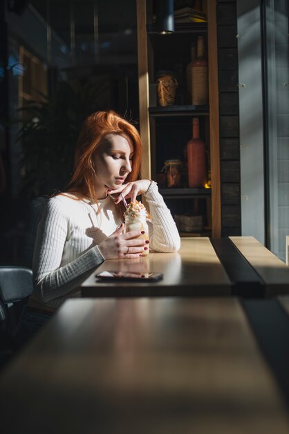 Schöne junge Frau, die Smoothieglas im Café hält