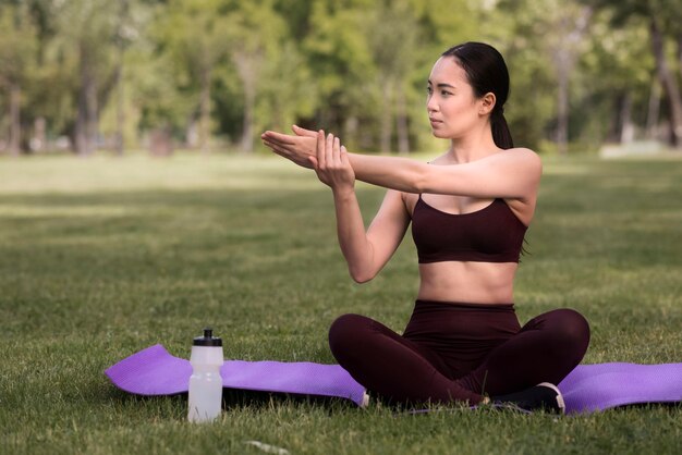 Schöne junge Frau, die Yoga im Freien tut