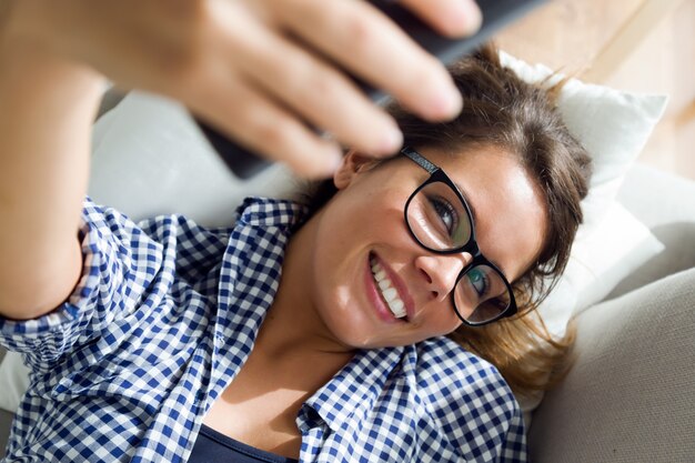 Schöne junge Frau, die zu Hause ein selfie nimmt.