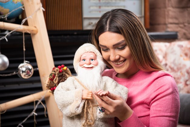 Schöne junge Frau, die zu Hause Puppe hält.