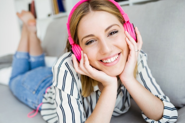 Schöne junge Frau hört Musik zu Hause.
