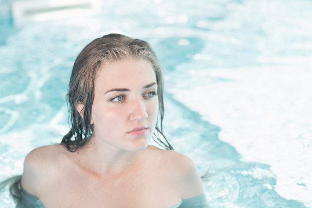 Schöne junge Frau im blauen Swimmingpool