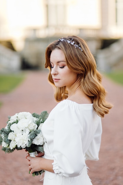 Schöne junge Frau im Hochzeitskleid, das auf der Straße in der Stadt aufwirft