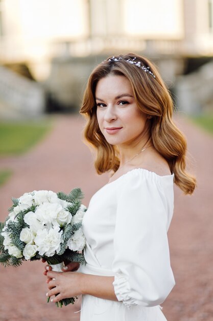 Schöne junge Frau im Hochzeitskleid, das auf der Straße in der Stadt aufwirft