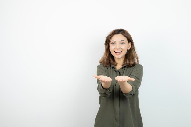 Schöne junge Frau im lässigen Outfit, die ihre geöffneten Handflächen zeigt. Foto in hoher Qualität