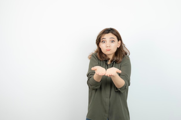 Schöne junge Frau im lässigen Outfit, die ihre geöffneten Handflächen zeigt. Foto in hoher Qualität