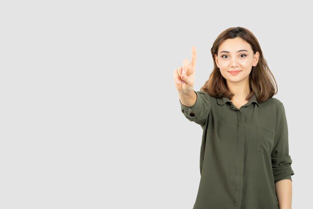 Schöne junge Frau im lässigen Outfit, die über weißer Wand steht