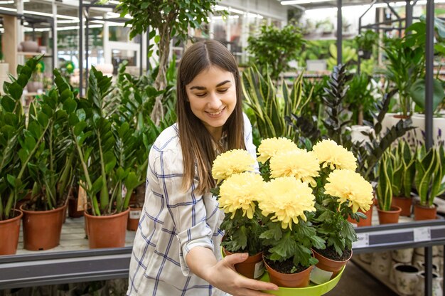 Schöne junge Frau in einem Blumenladen und Blumen wählen. Das Konzept von Gartenarbeit und Blumen.