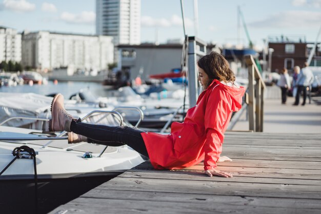 Schöne junge Frau in einem roten Mantel im Yachthafen. Stockholm, Schweden