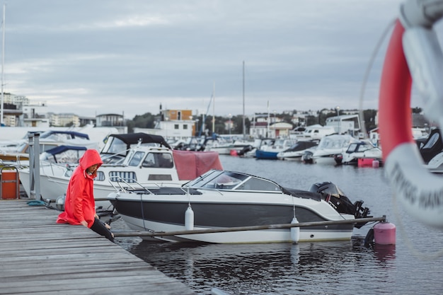 Kostenloses Foto schöne junge frau in einem roten mantel im yachthafen. stockholm, schweden