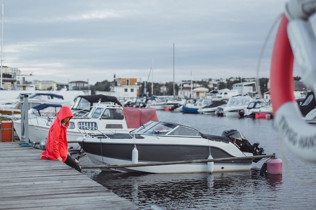 Schöne junge Frau in einem roten Mantel im Yachthafen. Stockholm, Schweden