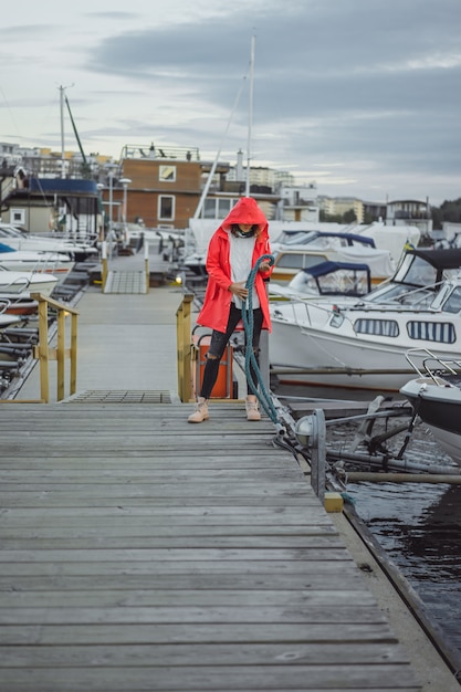 Schöne junge Frau in einem roten Mantel im Yachthafen. Stockholm, Schweden