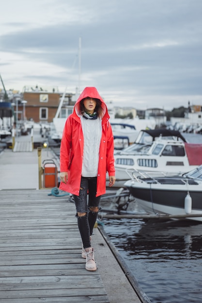 Schöne junge Frau in einem roten Mantel im Yachthafen. Stockholm, Schweden