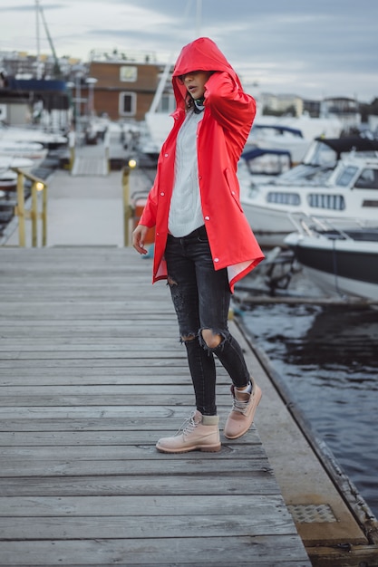 Schöne junge Frau in einem roten Mantel im Yachthafen. Stockholm, Schweden