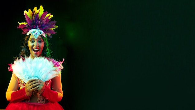 Schöne junge Frau in Karnevalsmaske, stilvolles Maskenkostüm mit Federn und Wunderkerzen, die einladend sind.