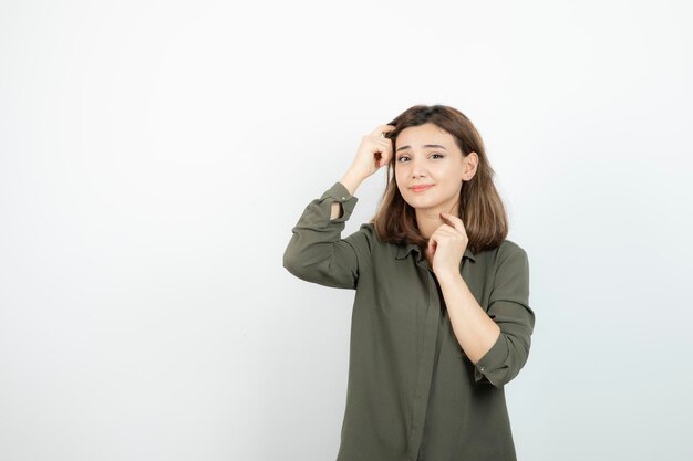 Schöne junge Frau in lässigem Outfit, die über einer weißen Wand steht. Foto in hoher Qualität