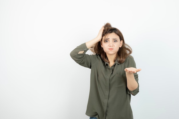 Schöne junge Frau in lässigem Outfit, die über einer weißen Wand steht. Foto in hoher Qualität