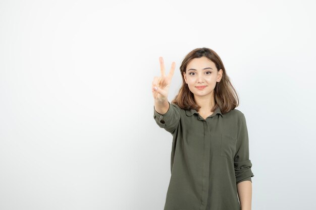 Schöne junge Frau in lässigem Outfit, die über einer weißen Wand steht. Foto in hoher Qualität