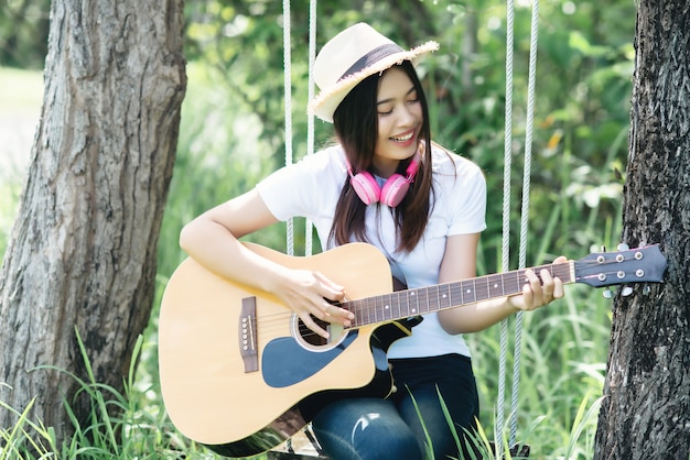 Schöne junge Frau mit Akustikgitarre an der Natur