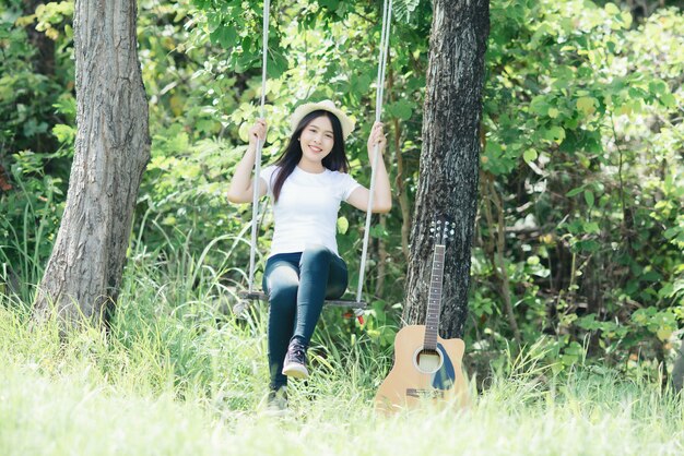 Schöne junge Frau mit Akustikgitarre an der Natur