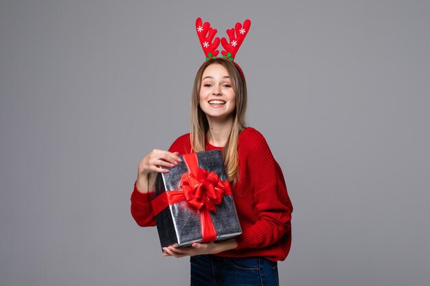Schöne junge Frau mit Geschenkbox tragen in roten Hörnern auf grauer Wand