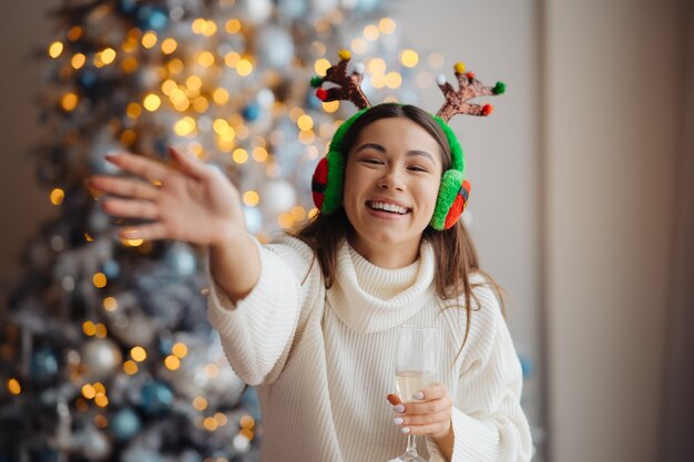 Schöne junge Frau mit Glas Champagner zu Hause. Weihnachtsfest