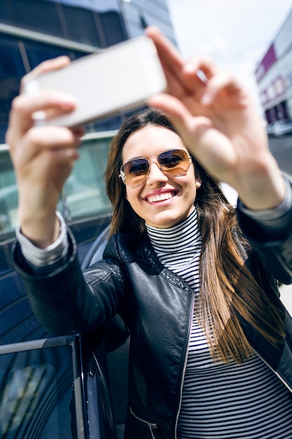 Schöne junge Frau mit ihrem Handy im Auto.