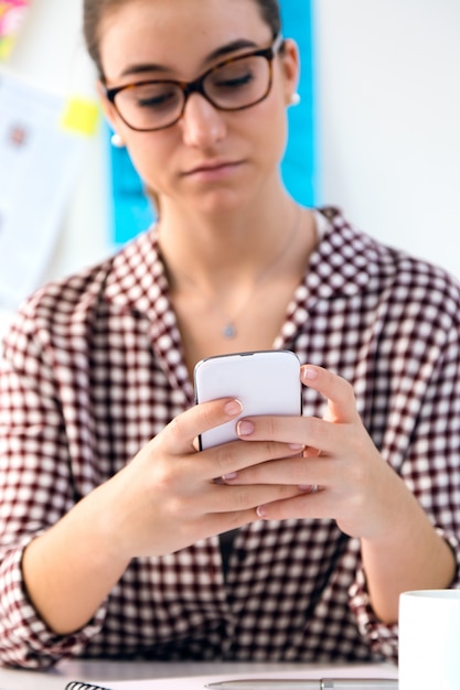 Kostenloses Foto schöne junge frau mit ihrem handy im büro.