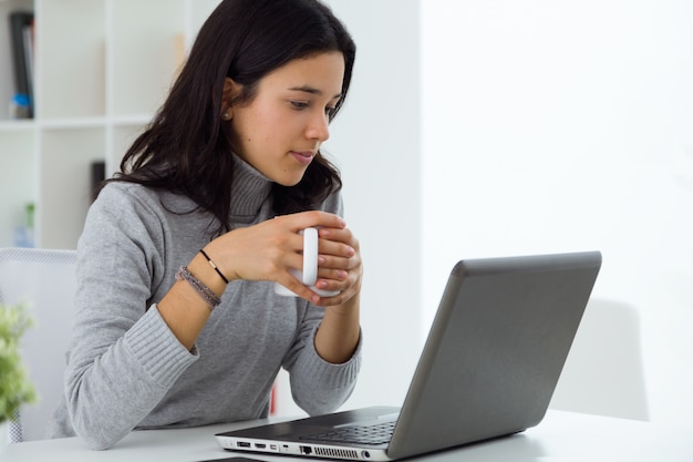 Schöne junge Frau mit ihrem Laptop zu Hause.