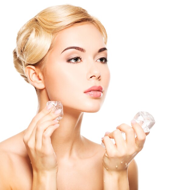 Schöne junge Frau trägt das Eis auf Gesicht. Hautpflegekonzept. Auf Weiß isoliert.