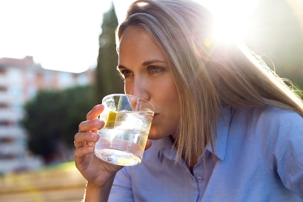 Schöne junge frau trinkt soda in einem restaurant terrasse.